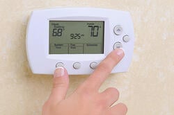 Person adjusting their residential thermostat