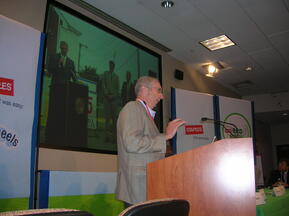 Man in a suit standing at a podium giving a speech