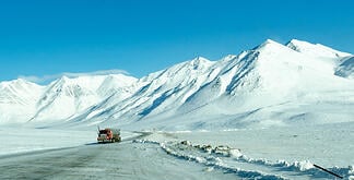 Semi-truck driving on a snowy mountain road