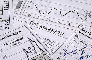 Image of various line graphics depicting the stock market scattered on a table