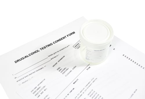 image of a urinalysis drug test container atop test page  